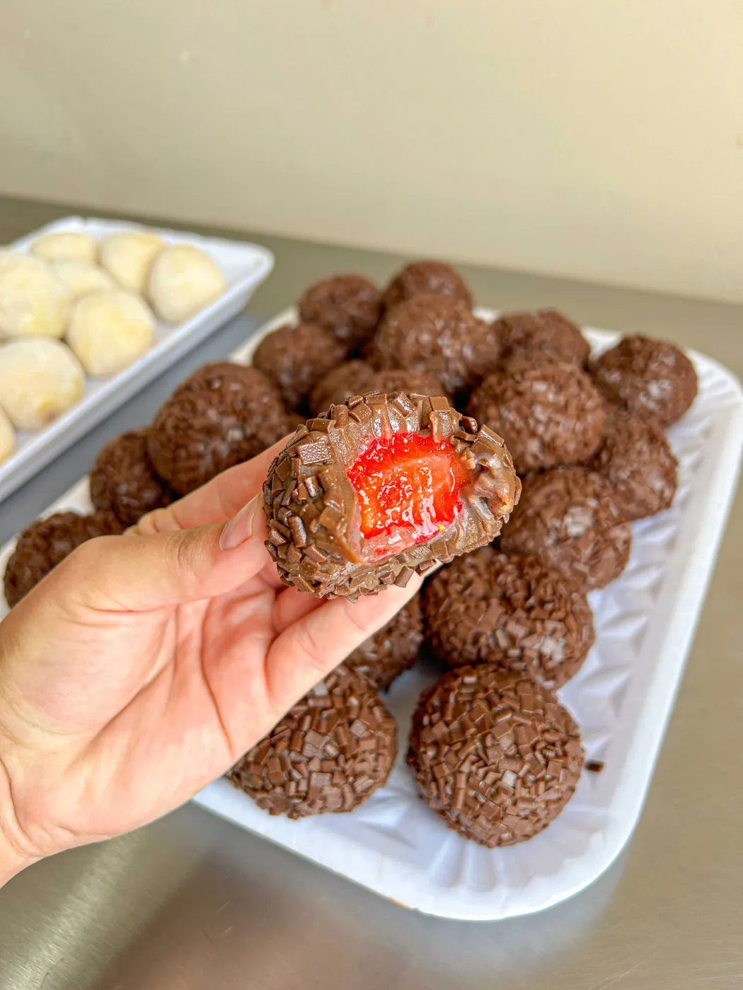 Coxinha de brigadeiro aberta mostrando o morango inteiro por dentro